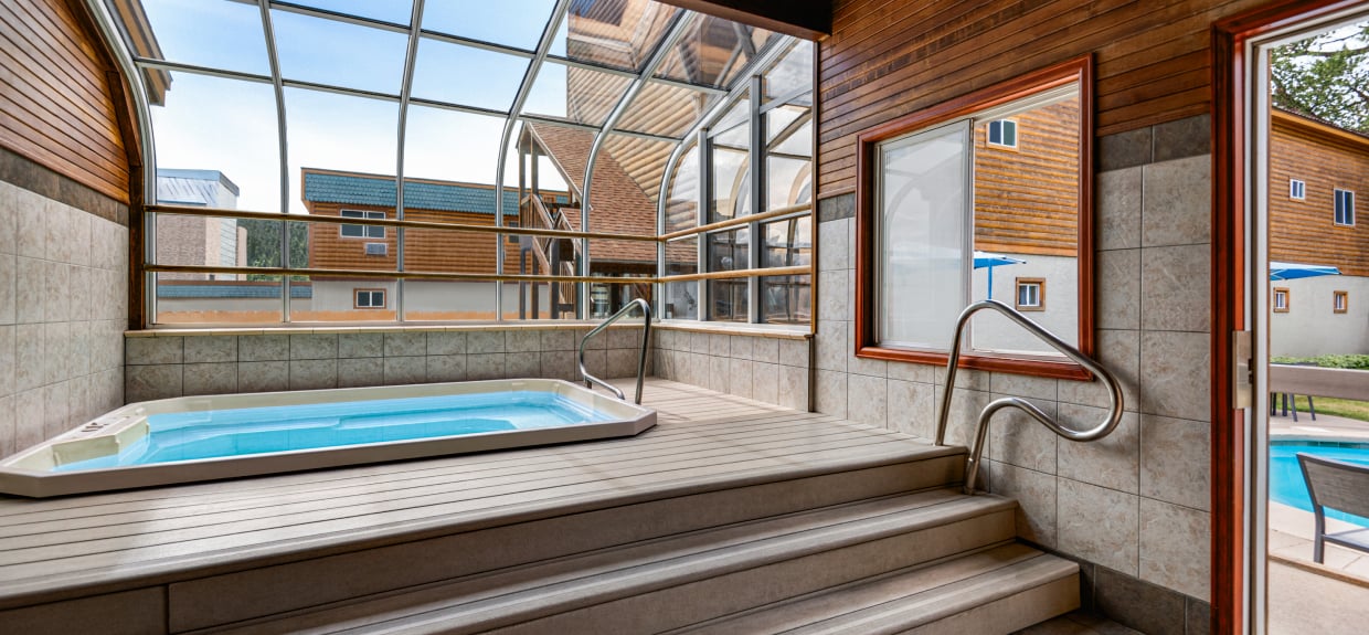 An indoor hot tub with a glass roof and wooden decking