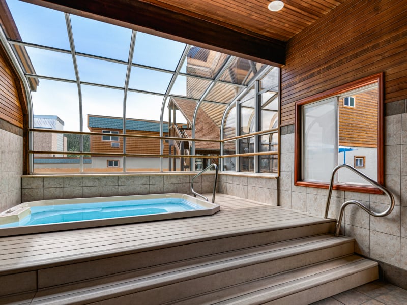 A small indoor pool with a glass roof and wooden deck
